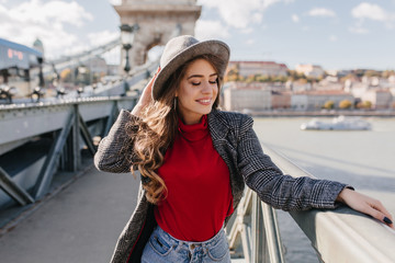 Wall Mural - beautiful white woman wears soft red sweater enjoying city views in travel. stunning young lady in t