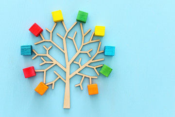 Business image of wooden tree with colorful cubes over blue table, human resources and management concept