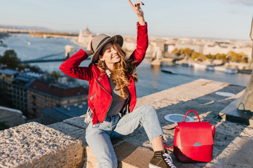 Wall Mural - girl in elegant hat and vintage pants funny posing on river background. outdoor portrait of graceful