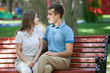 © biggur - Happy young couple in love sitting on a park bench and looking at camera
