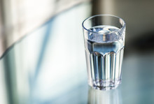 A Glass Of Water On Glass Table With Blurred Background