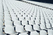 Rows of empty white plastic seats at the tribune in an open sports stadium