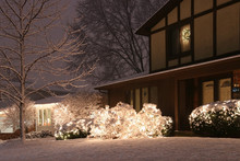 Beautiful Winter Blizzard Evening View. Front Yard Of The Private House Covered By Snow And Decorated For Winter Holiday Season Glowing In The Night. Christmas And New Year Background.