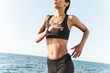 © Drobot Dean - Amazing young strong fitness woman outdoors at the beach at morning running.