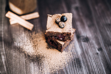 Wall Mural - brownie cake on a dark background decorated with fresh berries and cocoa