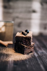 Wall Mural - brownie cake on a dark background decorated with fresh berries and cocoa