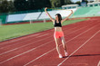 © lena_itzy - Portrait of happy young sports brunette woman in black top and rose shorts outdoors on stadium holding skipping rope over the head.