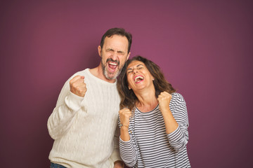 Sticker - Beautiful middle age couple wearing winter sweater over isolated purple background very happy and excited doing winner gesture with arms raised, smiling and screaming for success. Celebration concept.