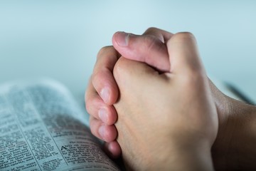 Closeup of Praying Hands over a Bible