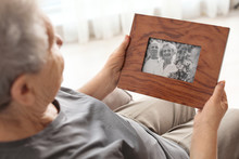Elderly Woman With Framed Family Portrait At Home