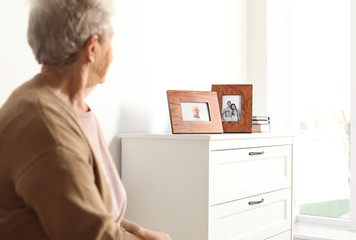 Sticker - Elderly woman looking at framed family portraits indoors