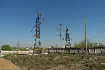 High voltage lines and power pylons in the industrial area on a Sunny day with a clear blue sky.