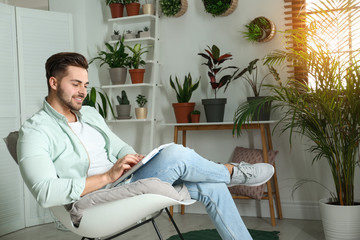 Wall Mural - Young man reading book in room with different home plants