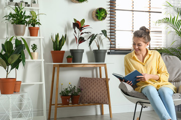 Poster - Young woman reading book in room with different home plants