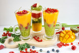 Fototapeta Kuchnia -  Kolorowe warstwowe smoothie z mango, kiwi, selera naciowego, malin, porzeczek, banana, jarmużu i kremu waniliowego
