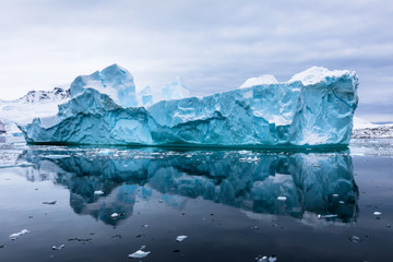 impressive iceberg with blue ice and beautiful reflection on water in antarctica, scenic landscape i