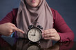 © airdone - Muslim Woman Holding Clock Pointing at Nine O'Clock, Lateness Concept