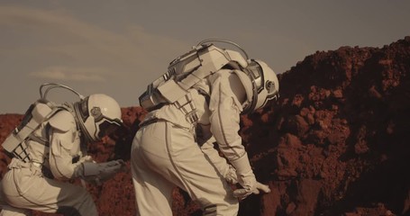 Wall Mural - Astronaut examining rock on Mars