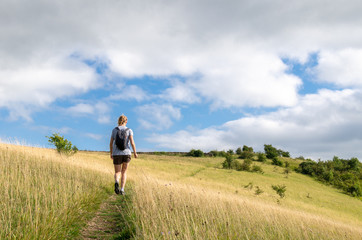 woman hiking on a field on the cotswold way, gloucestershire, england