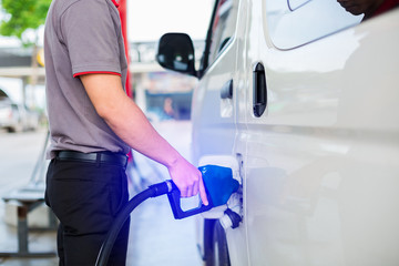 Hand refilling the white van with fuel at the gas station. Oil and gas energy.