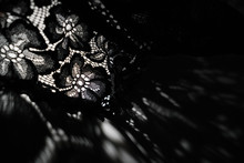 Abstract Background Of Shadows Black Floral Laces On White Table. Light Going Through Black Lace. Romantic, Passion Background For Sites, Flyers, Package