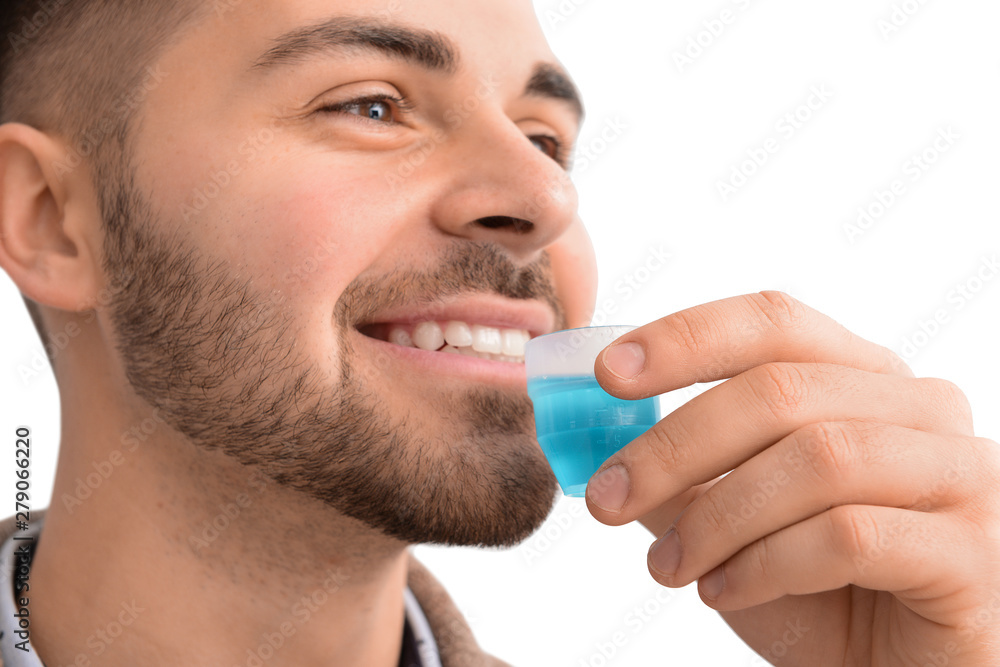 Handsome man with mouthwash on light background, closeup