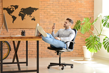 Poster - Handsome man with mobile phone resting in office