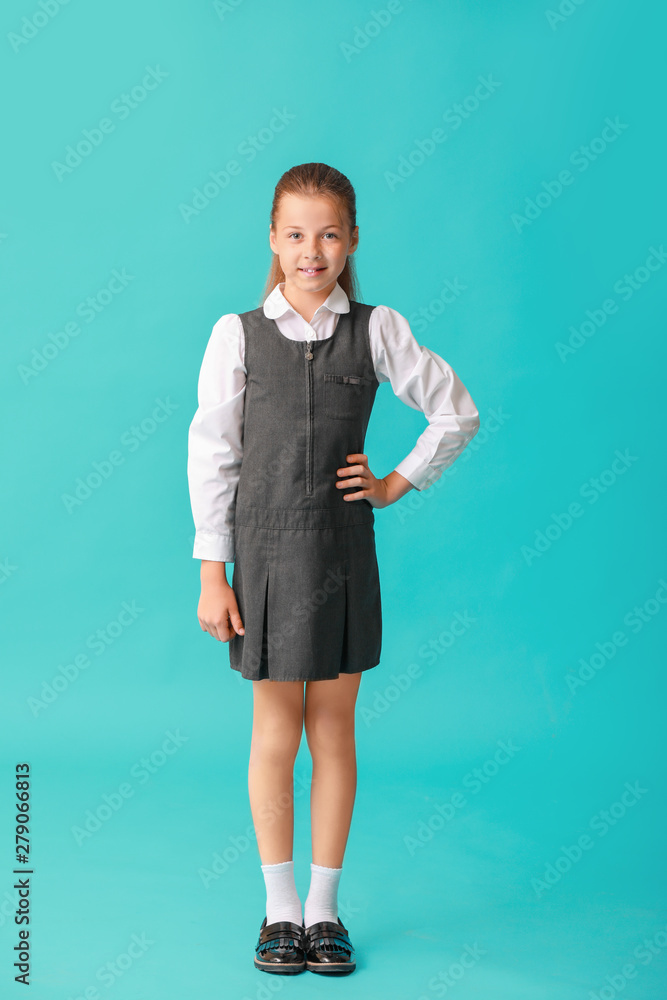 Cute little schoolgirl on color background