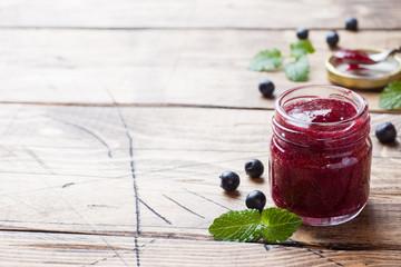 Jar of homemade blueberry jam on a wooden background. Copy space