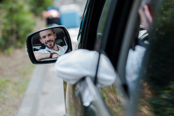 Wall Mural - selective focus of cheerful man looking at car window and smiling in car