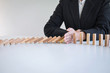 © Ngampol - Risk and Strategy in Business, Image of hand stopping falling collapse wooden block dominoes effect from continuous toppled block, prevention and development to stability