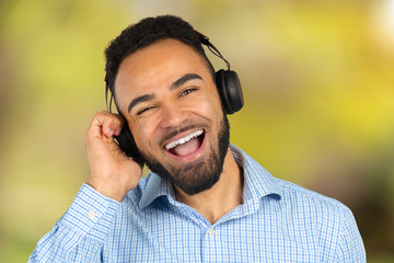 Wall Mural - Happy african man smiling listening to music in headphones. White background