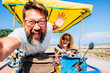 Crazy people happy couple have fun on vacation driving together a bike - tourist and happiness for adult man and woman enjoying the summer holiday . sea and beach in background - focus on woman