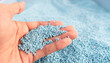 © ZETHA_WORK - Hand on large pile of blue plastic granules in temporary storage of production line at recycle factory, masterbatch dye polymer plastics resin pellet background,  injection molding process lab