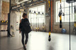 © Friends Stock - Morning workout. Back view of young athletic woman carrying her sport bag and looking aside while standing at empty gym.