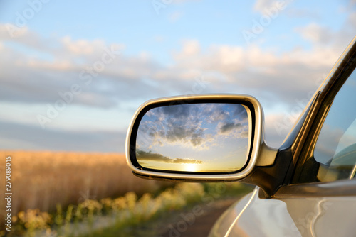 Cuadros en Lienzo Sunset sky reflect in rearview mirror of car.