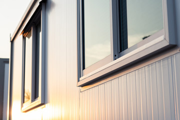 Wall Mural - beautiful warm sunrise light shining on house glass window with town nature reflection in the morning, modern home exterior view