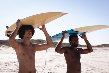 Young men carrying their surfboards on their head at the beach