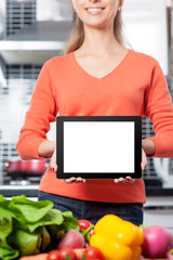 Wall Mural - woman holding digital tablet standing in her kitchen