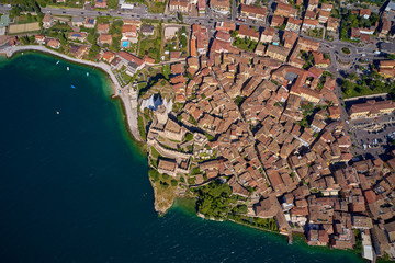 Aerial photography with drone, on the medieval lakeside castle with a museum of history and paleontology, as well as a panoramic view from the tower. City of Malcesine on Lake Garda, Italy.