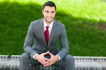 Wall Mural - Business man portrait sitting on a bench outdoor