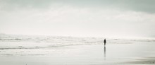 Panoramic Shot Of A Silhouette Of A Woman In A Dress Walking On The Beach With Amazing White Clouds