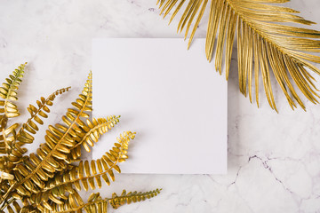 Creative layout made of golden tropical leaves and palms on white marble texture background. Minimal summer exotic concept with copy space. Border arrangement background.