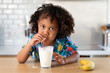 © Lisa Tichané - Young girl with afro hair blowing bubbles in a glass of milk