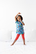 © Lisa Tichané - Young child singing with hairbrush as a microphone dancing on bed