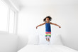 © Lisa Tichané - Young girl with afro hair jumping on bed