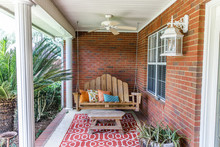 Colorful And Modern Bohemian Boho Outdoor Front Porch Decoration With Seating And A Plant. The House Is Red Brick And Traditional.