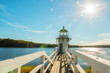 canvas print picture - Lighthouse on the bay. Doubling Point Light is a lighthouse on the Kennebec River in Arrovich, Maine. USA. Maine. Beautiful green shores of the reservoir and the village bridge to the lighthouse.