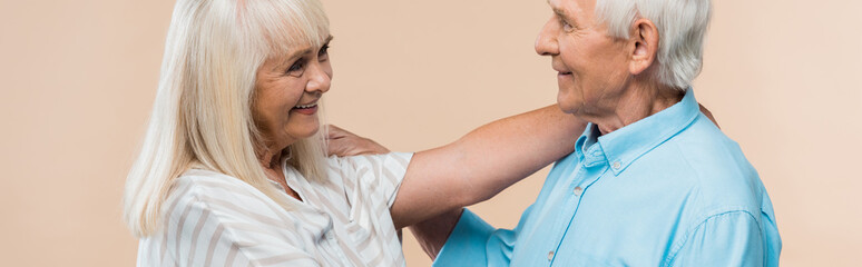 Wall Mural - panoramic shot of senior woman smiling while looking at pensioner isolated on beige