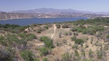 Aerial Drone Shot Of A Dirt Trail Leading To A Mountain Lake (Cachuma Lake, California)